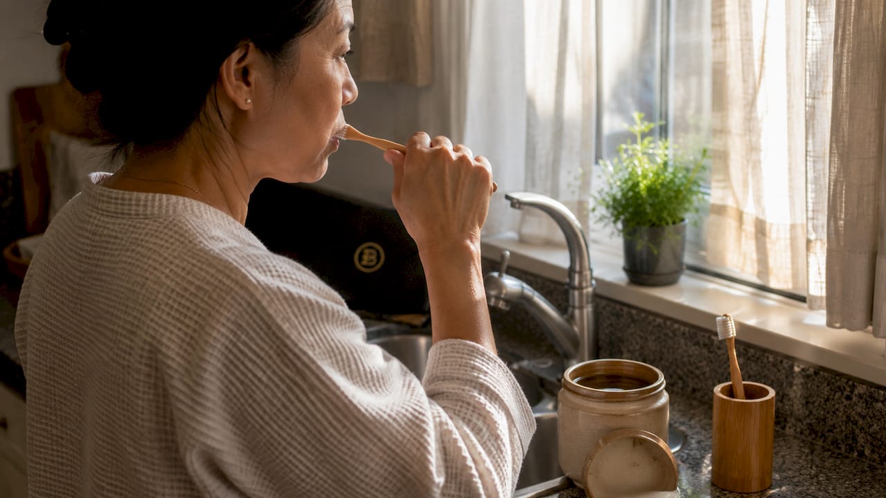 Woman brushing teeth at home bathroom
