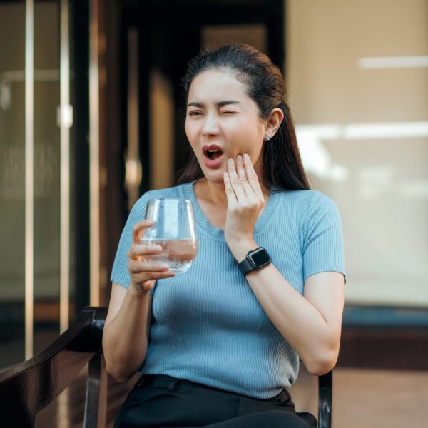 Asian  adult Woman hypersensitive teeth pain after Drinking Cold water with ice while sitting in the yard at home